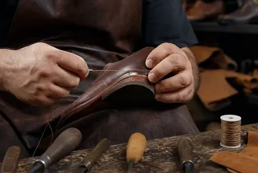 Sapateiro realizando costura em um calçado.